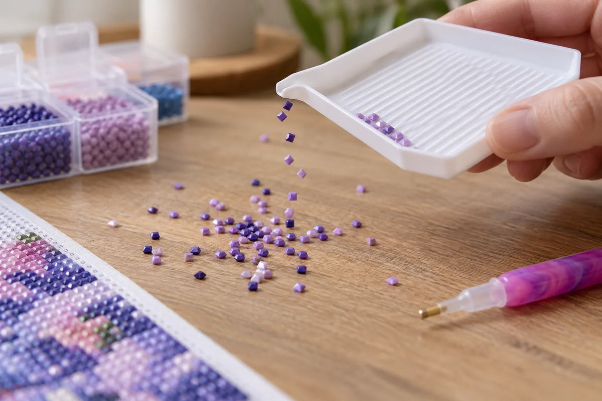 Diamond painting drills clinging near a tray while a crafter sorts colors at a clean work surface