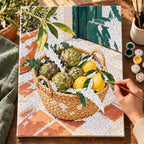 `04-artichokes-lemons-market-basket-painting-process.webp` — Painting process scene for the Artichokes Lemons Market Basket kit, with the complete numbered canvas and painting tools.