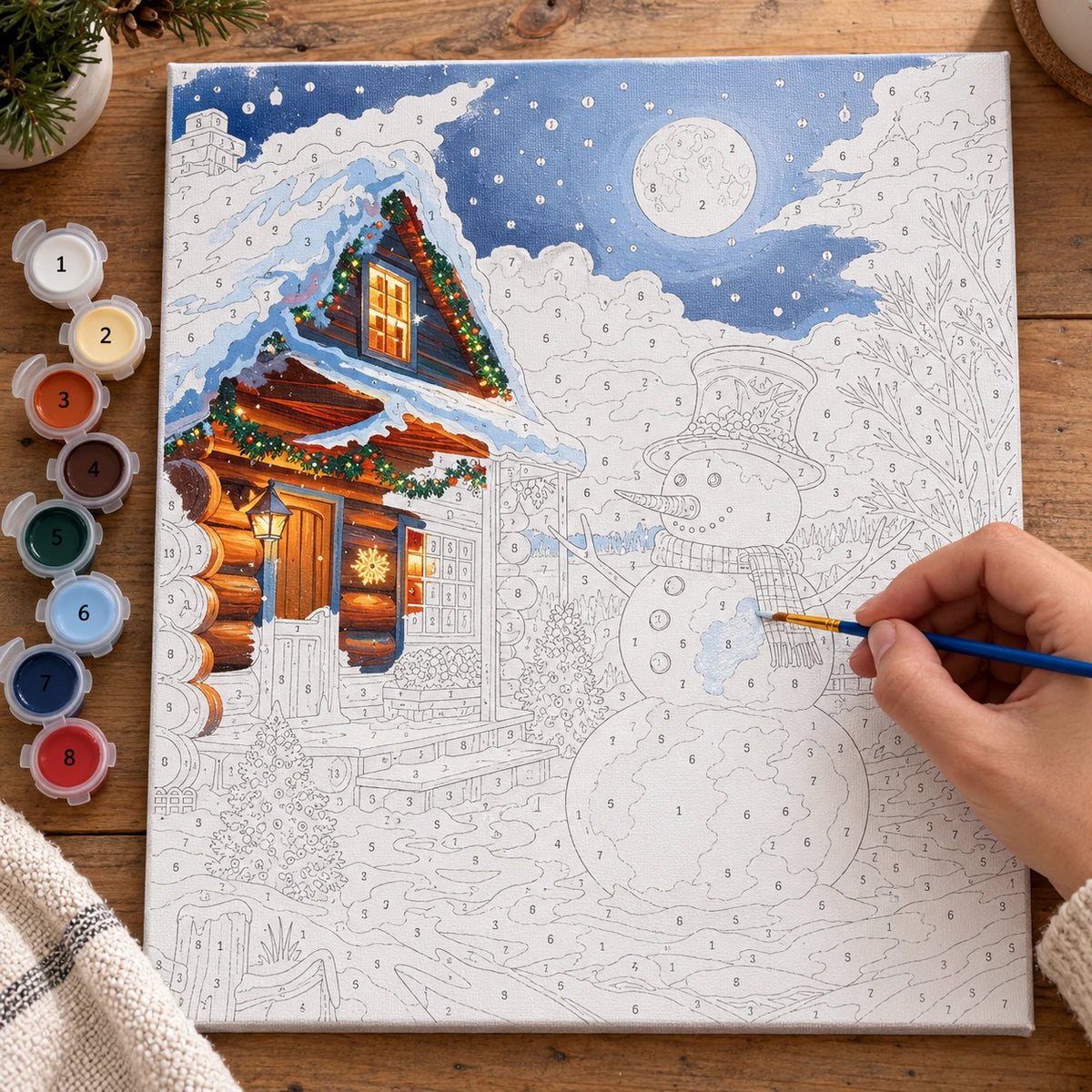 Complete Moonlit Snowman Cabin numbered canvas being painted with acrylic paints and brushes