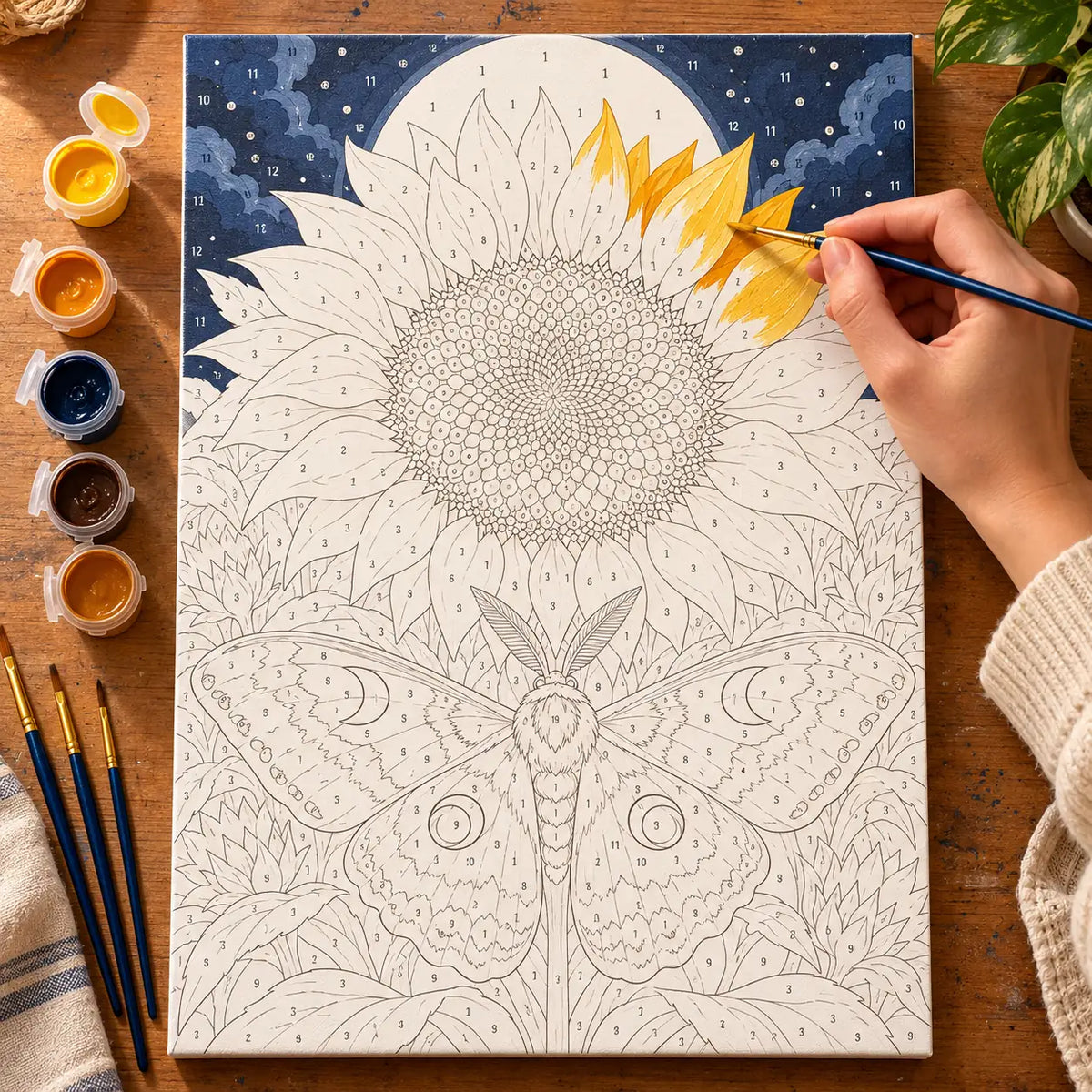 Painting process scene for the Moth Oracle Sunflower Disc kit, with the complete numbered canvas and painting tools.