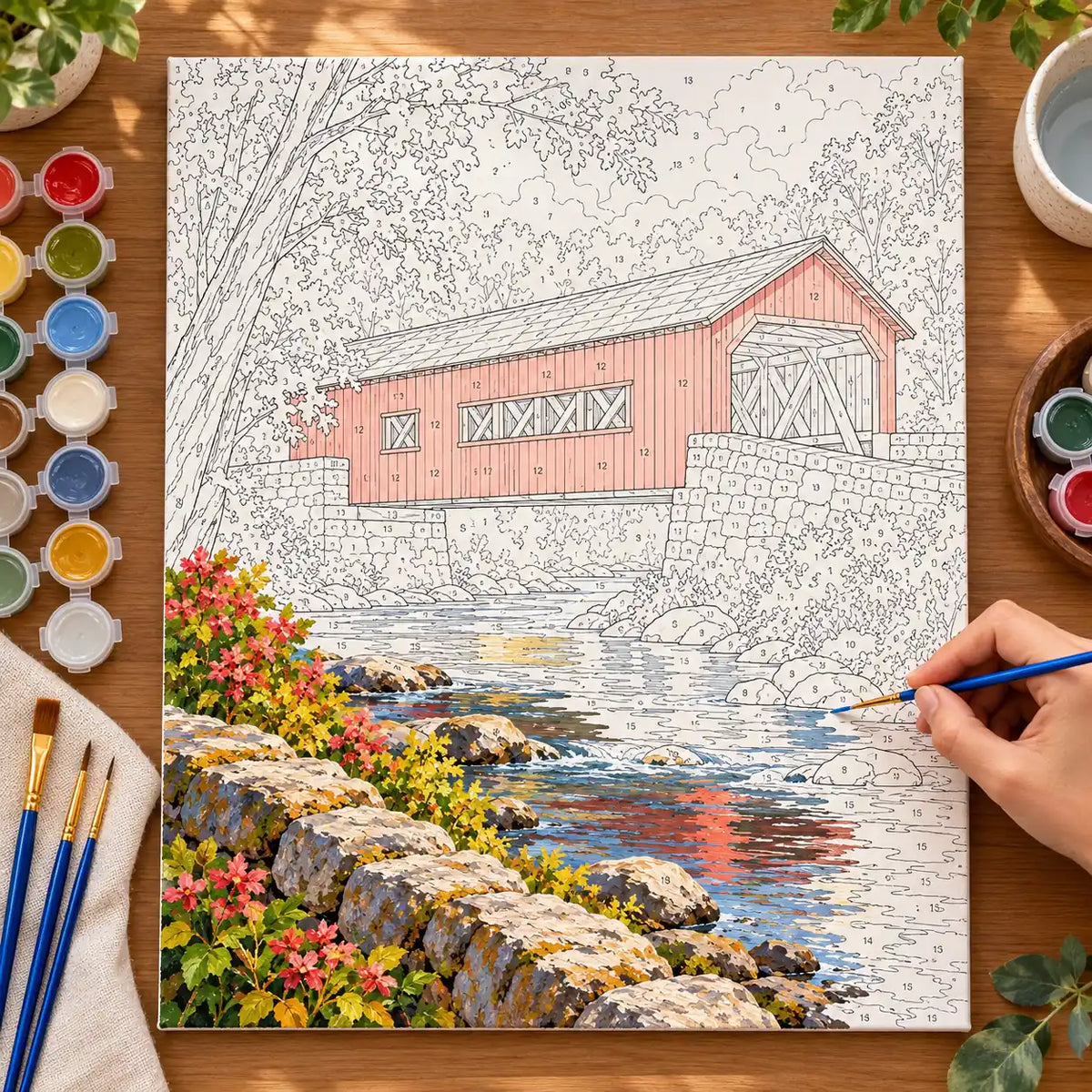 `04-new-england-covered-bridge-painting-process.webp` — Full painting process scene for the New England Covered Bridge kit, with the complete numbered canvas and painting tools visible.