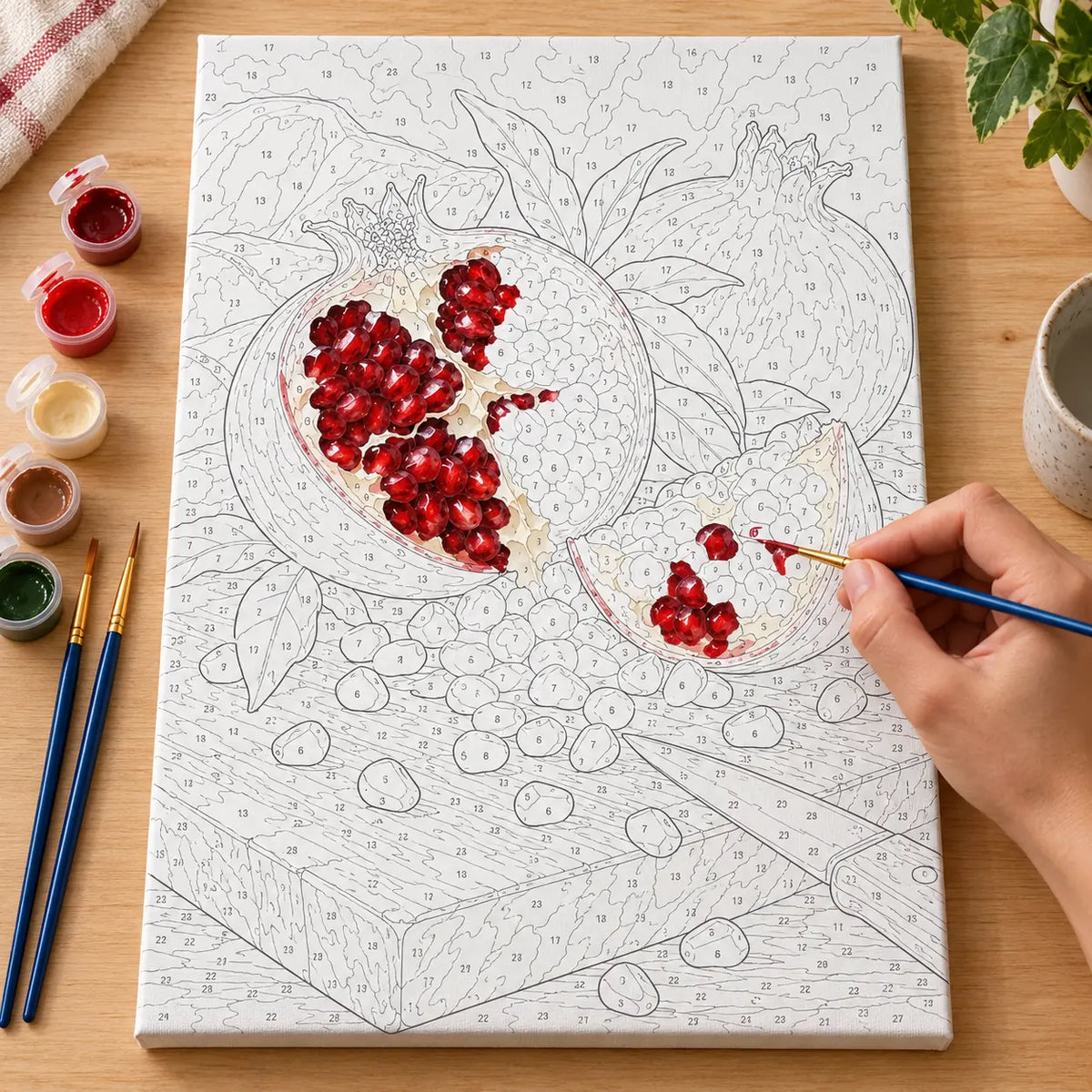 Painting process scene for the Pomegranate Seeds Dark Board kit, with the complete numbered canvas and painting tools.