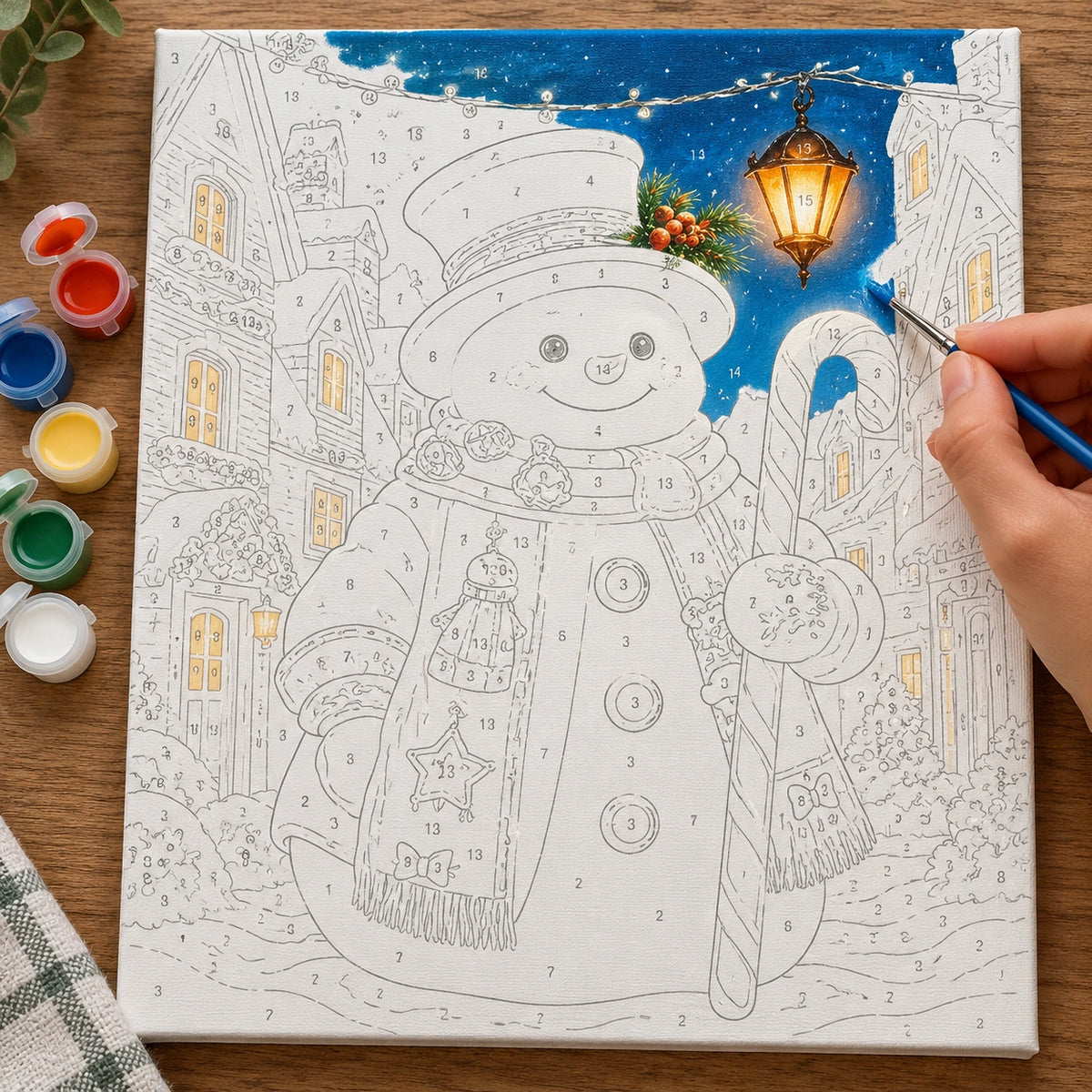 Complete Snowman’s Lanternlit Welcome numbered canvas being painted with acrylic paints and brushes