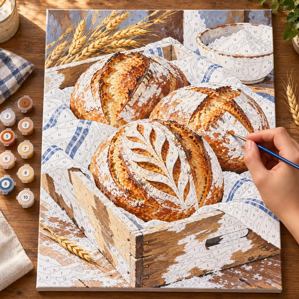 `04-sourdough-loaves-bakery-crate-painting-process.webp` — Painting process scene for the Sourdough Loaves Bakery Crate kit, with the complete numbered canvas and painting tools.