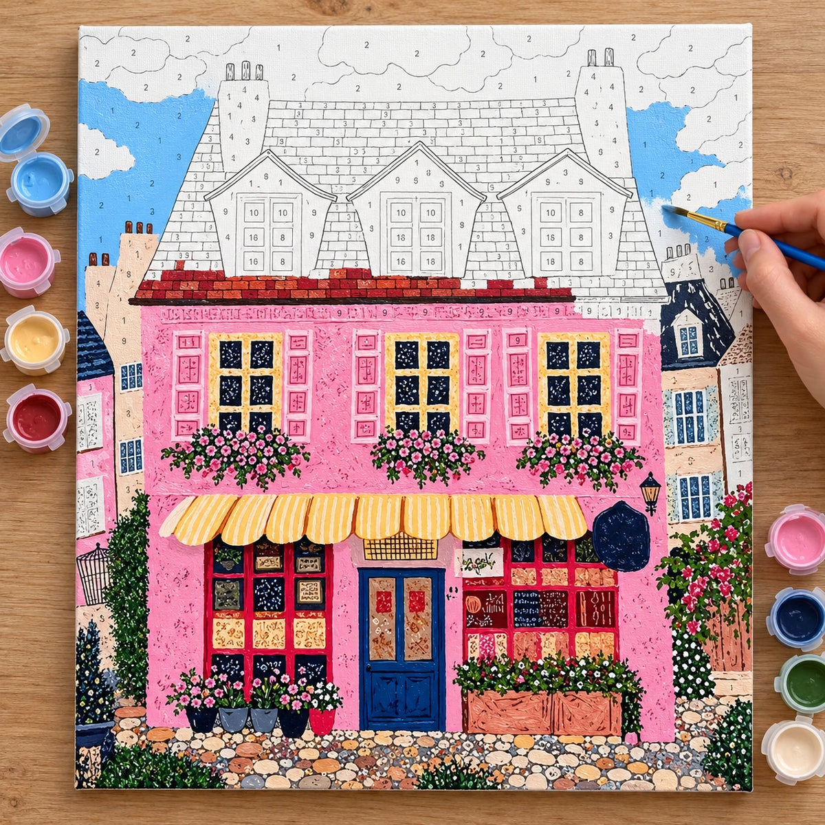 Whimsical Pink Bakery Storefront Paint by Numbers numbered canvas being painted with acrylic paints and brushes