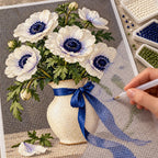 White anemones with deep navy centers and green leaves in a ceramic vase tied with a cobalt ribbon: diamond painting in progress with a pen
