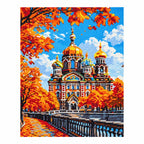 Finished diamond painting showing an ornate cathedral with golden domes among orange autumn leaves.