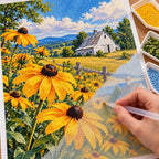 Golden black-eyed Susans in a sunny country field around a white barn: diamond painting in progress with a pen