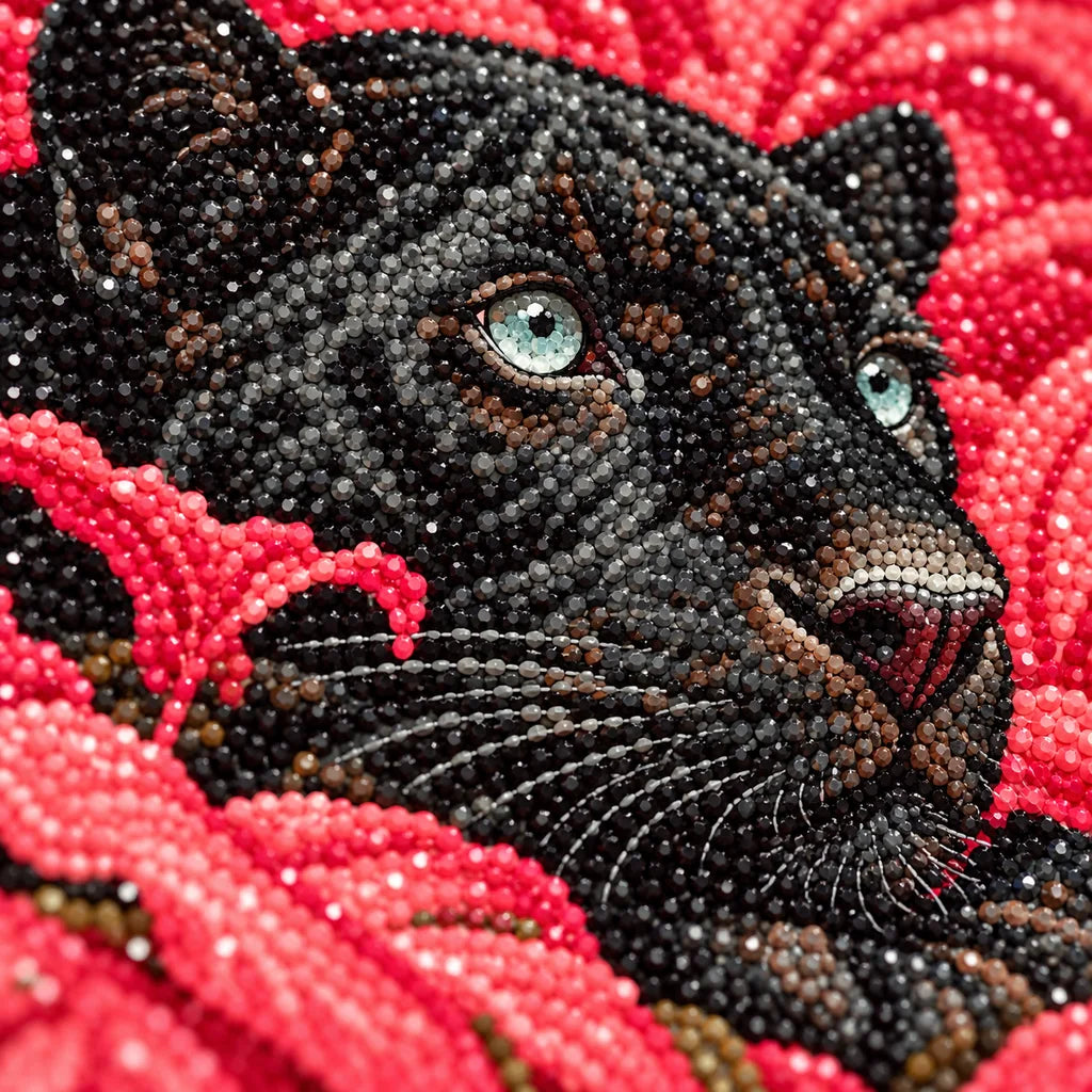 Close-up of diamond drills on artwork of a black panther reclining among vivid coral leaves.