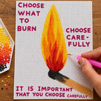 Diamond painting process for Choose What to Burn Match Art Diamond Painting Kit, with drills being placed over a single upright flame beside the words “Choose What to Burn”.