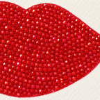 Close-up of diamond drill details in playful red lip motifs with a kiss message.