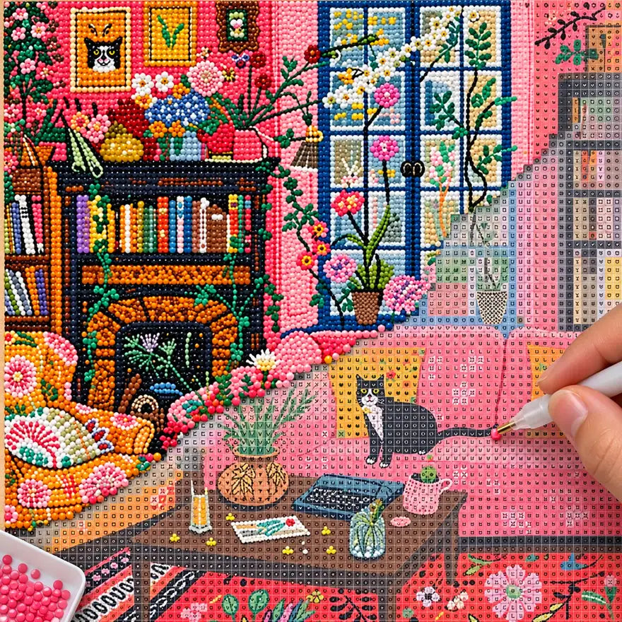 Diamond painting process showing a black cat in a flower-filled living room being completed with a stylus