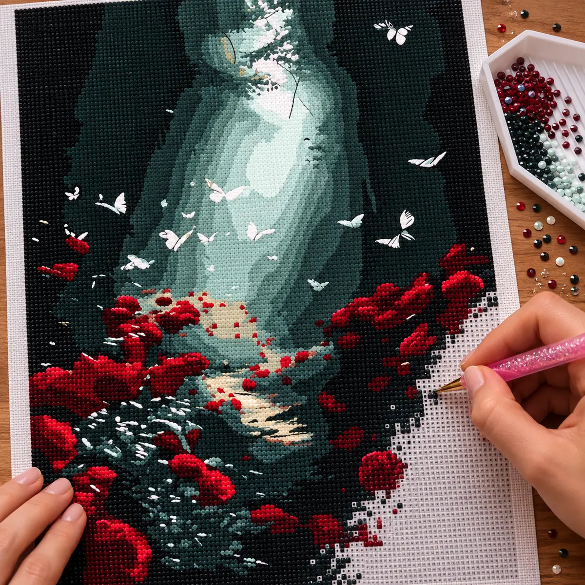 Making the Forest Light And Butterflies diamond painting, with hands placing drills over a light-filled woodland path with butterflies and red flowers.