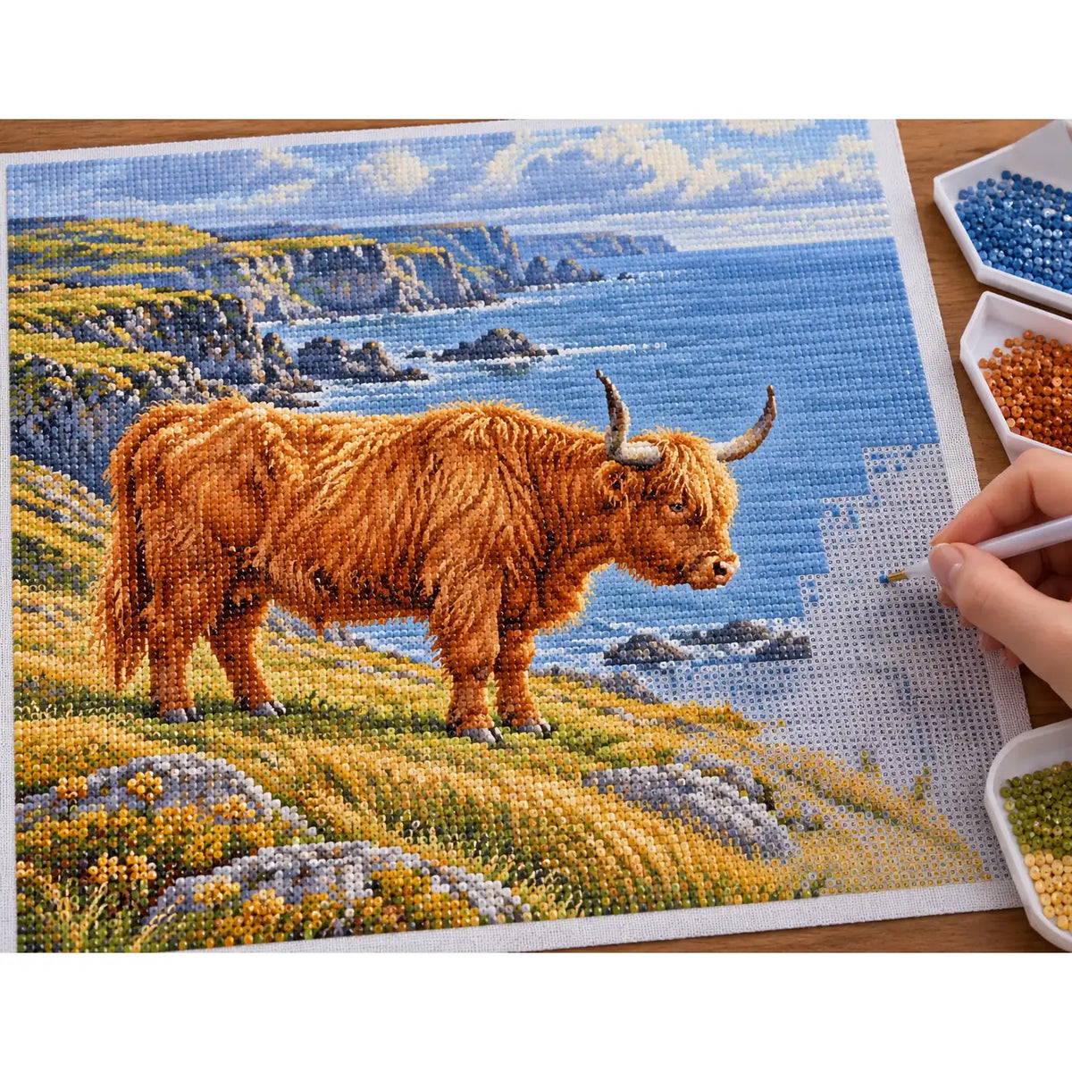 Hands placing drills on the Highland Cow Coastal Profile diamond painting canvas