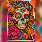 Diamond painting process showing a colorful jeweled sugar skull surrounded by marigolds and roses being completed with a stylus