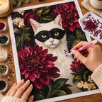 Hands placing diamonds on the masked cat and dahlia design