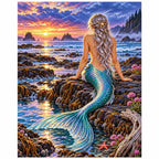 White-background finished diamond painting of a mermaid at a rocky tide pool at sunset