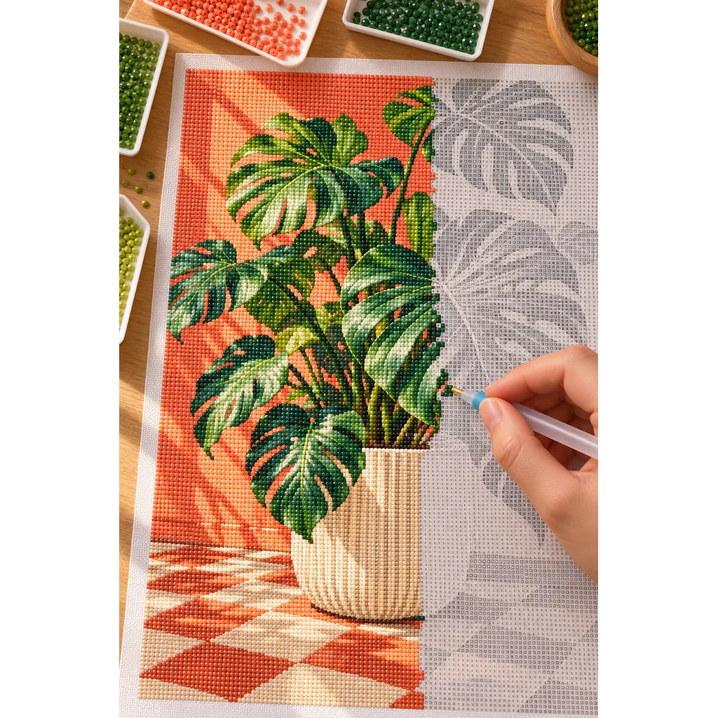 Glossy monstera leaves in a cream planter against a coral wall and checkerboard floor: diamond painting in progress with a pen
