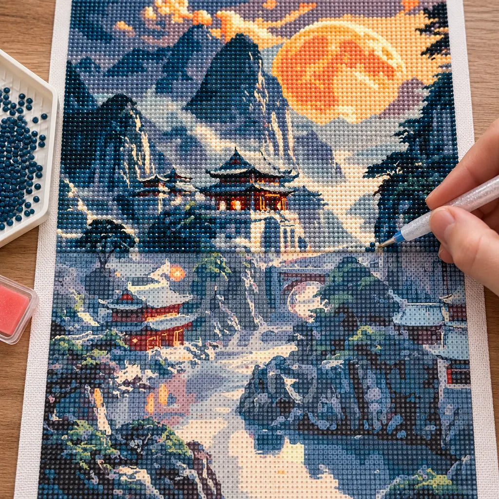 Diamond painting process for Moonlit Mountain Sanctuary, showing drills being placed over a sanctuary among steep mountain peaks under a glowing moon.