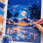 Diamond painting process for Moonrise Over Palm Lagoon Diamond Painting Kit, with hands applying drills over a palm silhouettes, a full moon and sunset reflections over a tropical lagoon.