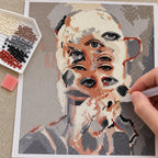 Hands applying diamond drills to a cubist portrait of overlapping human and dog faces.