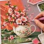 Pink peach blossoms growing from a teapot: diamond painting being completed with a pen