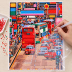 Hands applying drills to a canvas showing a busy Kowloon street with red double-decker buses and dense city traffic.