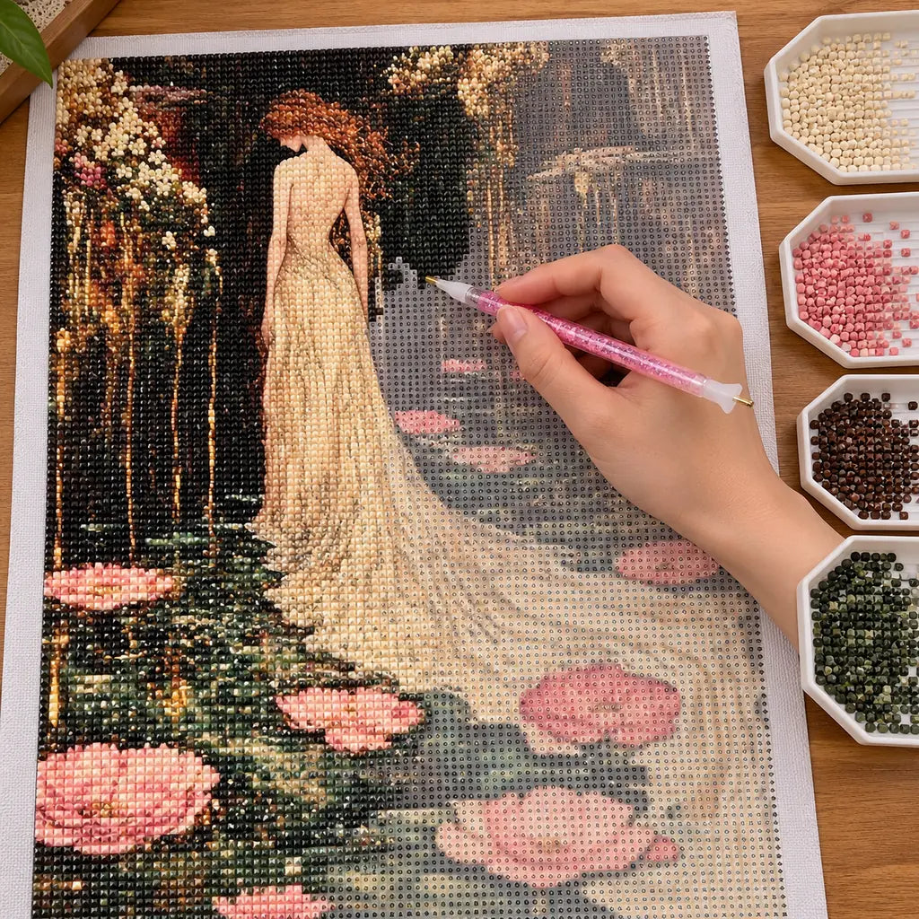 Hands applying drills to a canvas with a woman in a flowing gown beside pink lotus flowers.