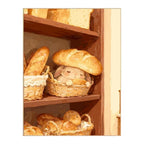White-background original artwork of a sleepy bunny tucked into a woven bread basket beneath a loaf