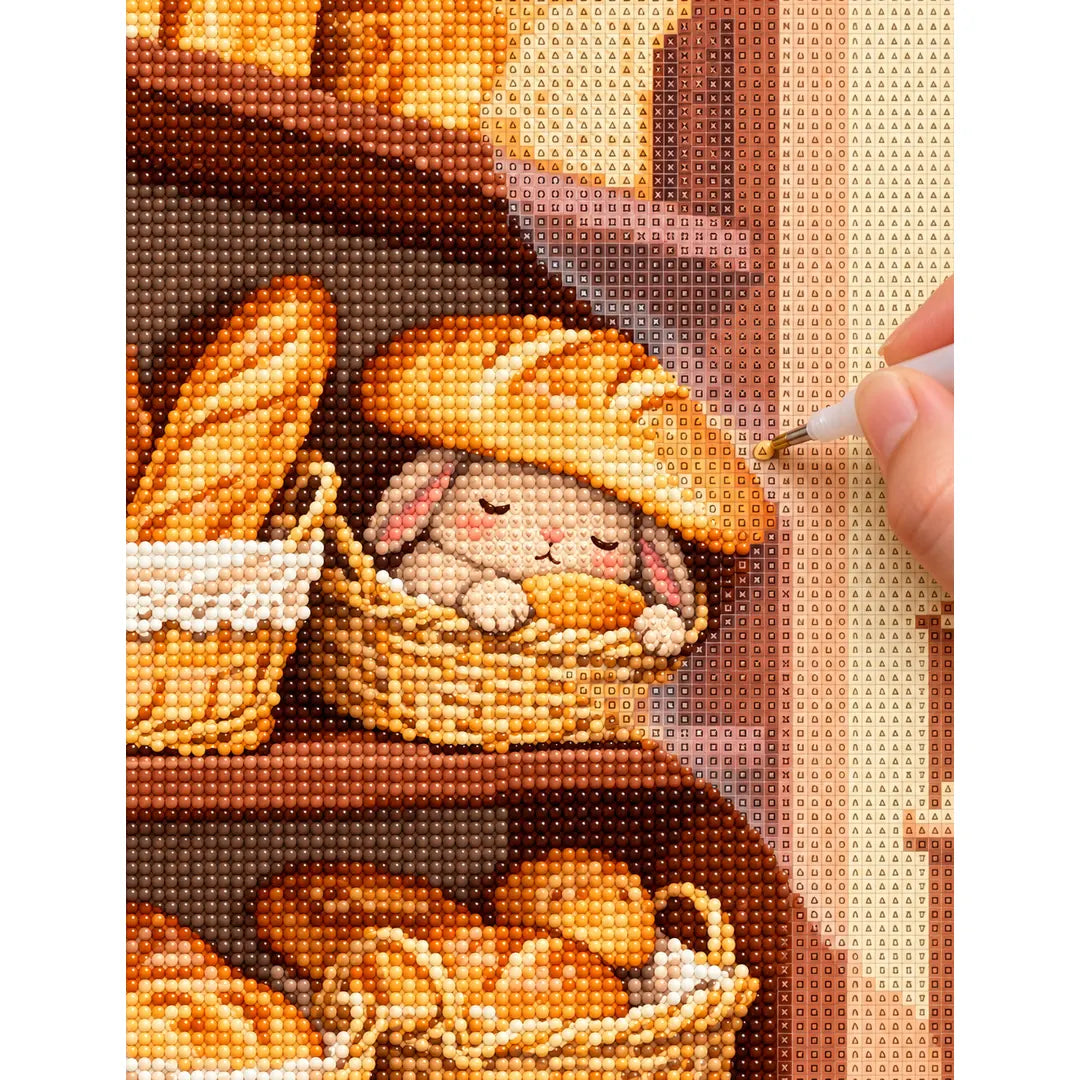 Diamond painting process showing a sleepy bunny in a bread basket being completed with a stylus