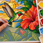 Hands placing drills on the stained glass hummingbird and hibiscus design