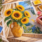 Golden sunflowers in an ochre vase beside a blue window: diamond painting being completed with a pen