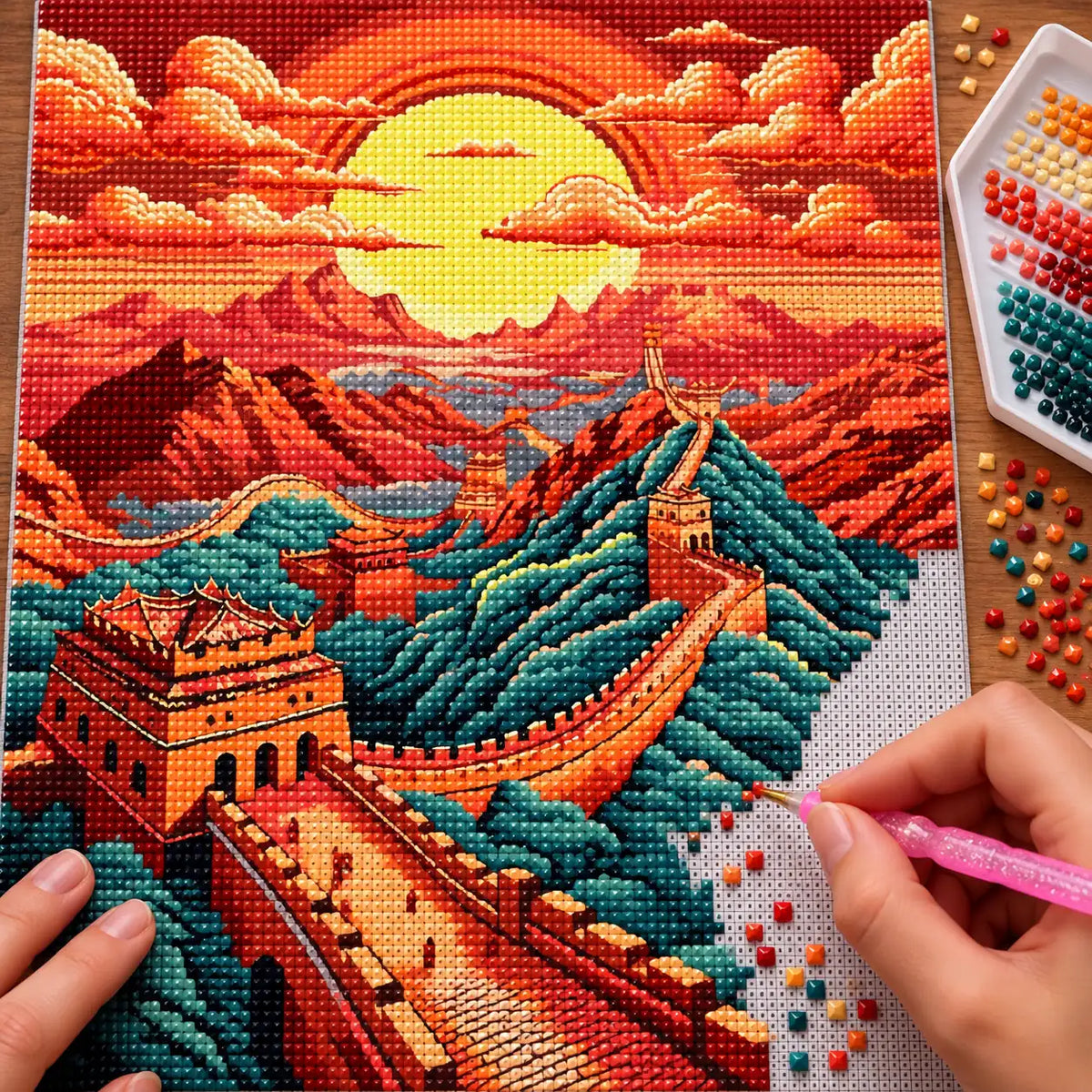Making the Sunset Over The Great Wall diamond painting, with hands placing drills over the Great Wall winding across mountain ridges beneath a red-orange sunset.