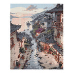 Finished diamond painting of traditional riverside village homes reflected along a stream beneath sunset clouds.