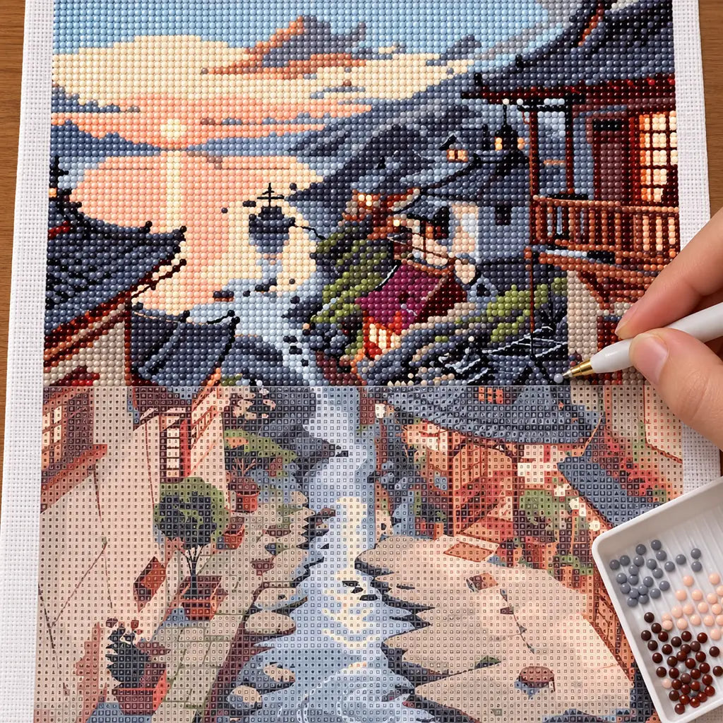 Diamond painting process for Sunset Village by the Stream, showing drills being placed over traditional riverside village homes reflected along a stream beneath sunset clouds.