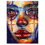 Finished diamond painting of a tear-streaked cubist woman portrait in vivid colors.