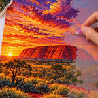 Hands placing diamond drills on the Uluru Sunset design.