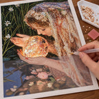 Diamond painting process for Veiled Seer Crystal Orb, with drills being placed over a mystical figure holding a crystal orb in a leafy, moonlit setting.