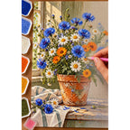 Colorful wildflowers growing in a terracotta pot: diamond painting being completed with a pen