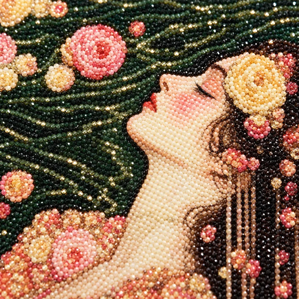 Close-up of diamond drills on artwork of a woman in a floral gown floating among roses on dark water.
